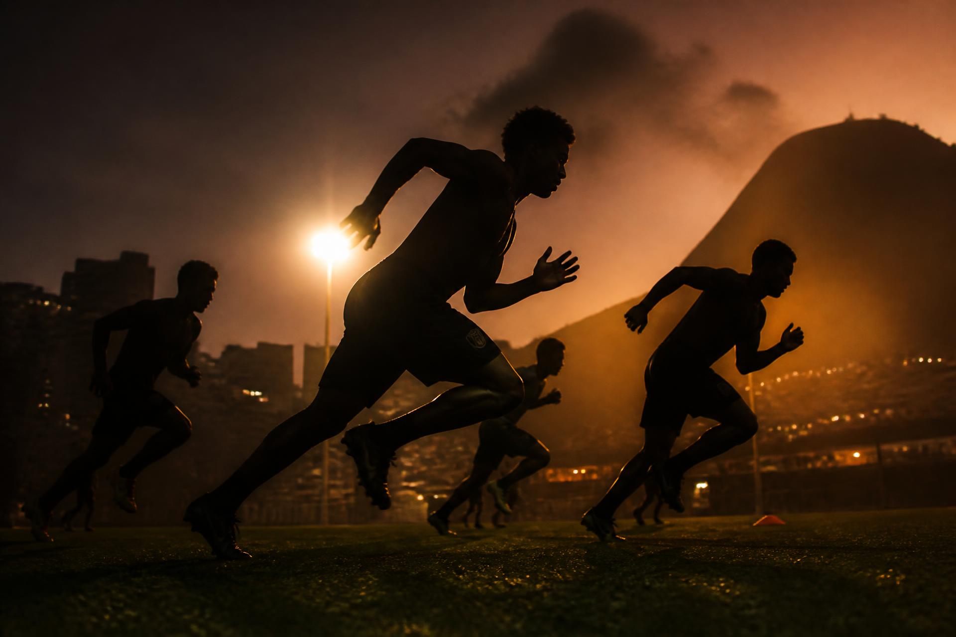 Footballers sprinting under floodlights at dusk